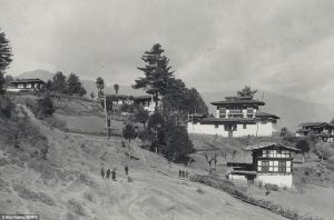 Bhutan circa 1900s: Black and white image of traditional Bhutanese buildings dotting a hillside landscape, historic architecture.