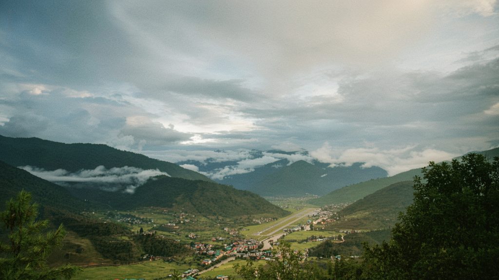 Scenic Bhutan landscape: Lush green valleys, winding river, and misty mountains. Travel to Bhutan for breathtaking views.